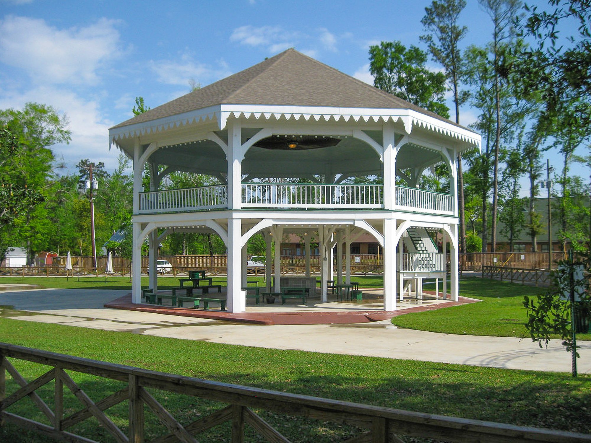The historic white pavilion in Abita Springs park, surrounded by greenery and paved pathways